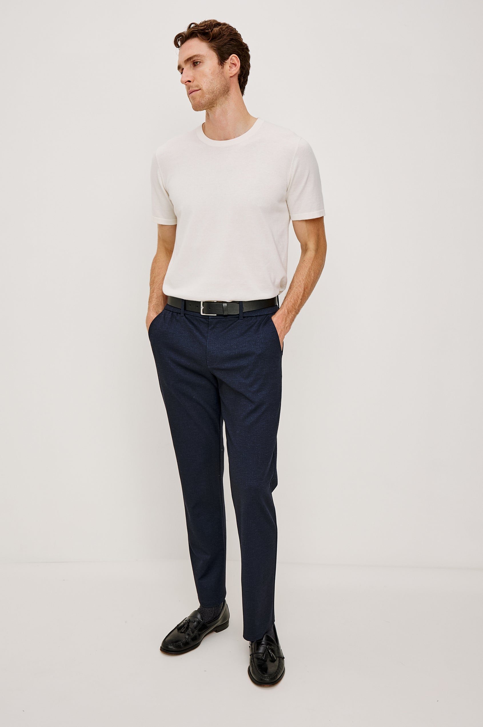 The Olivier is a trouser with a front zip fly, belt loops, side pockets, and pintuck detailing in Navy colorway. Front full body view featured on model.