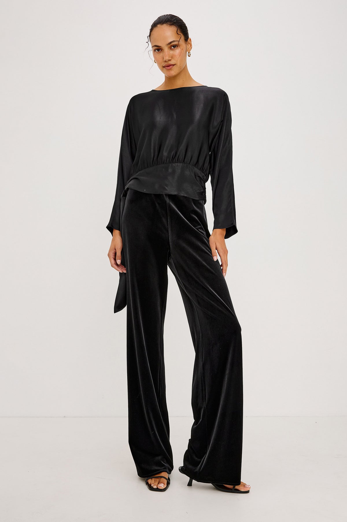 Opal Long-Sleeve Top in Luxe Satin With a Self Tie Hem in Black Colorway - Front Full Body View Featured on Model.