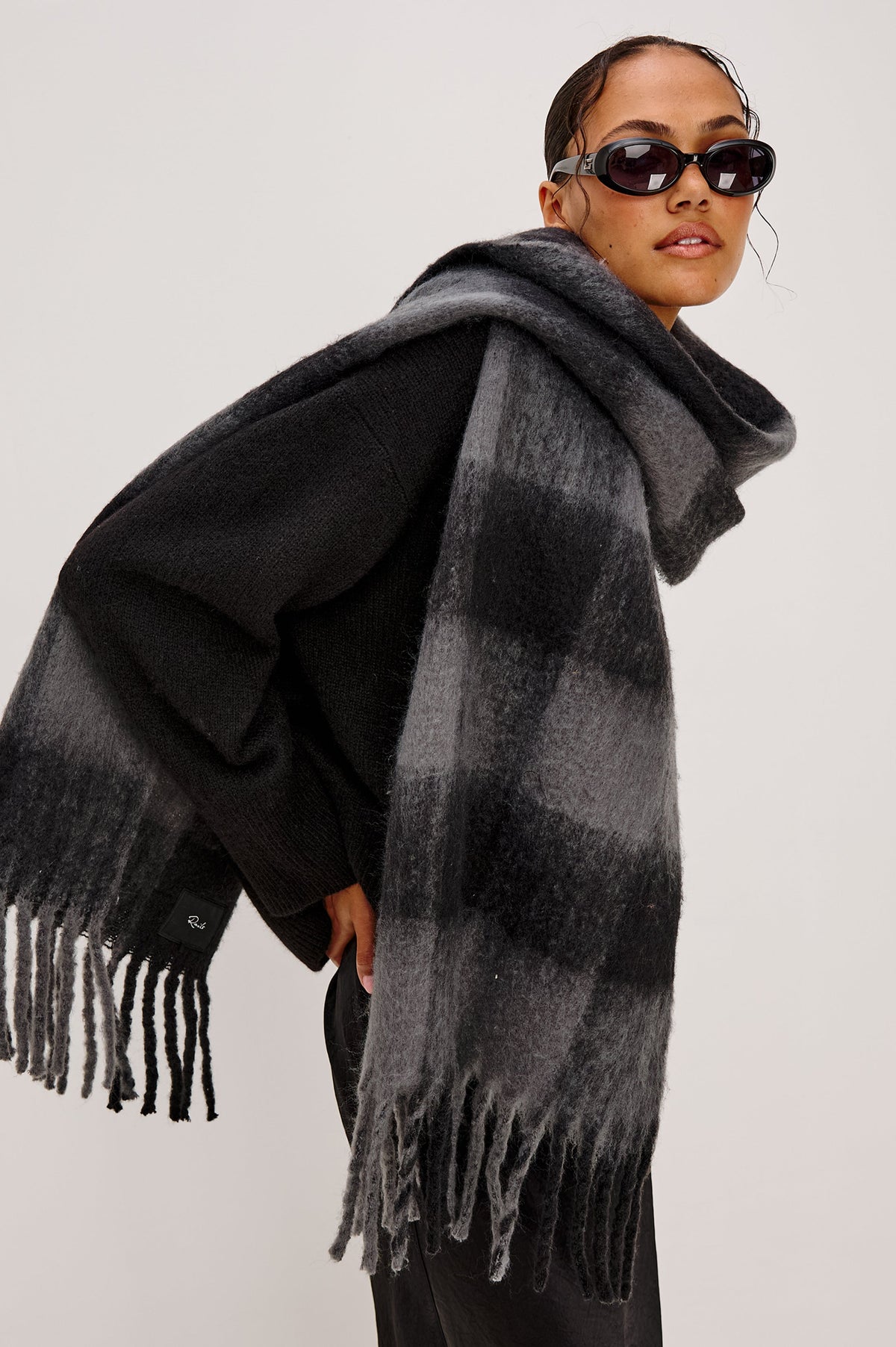Oslo Scarf with Twisted Tassels and a Checkered Pattern in Charcoal Black Colorway - Side View Featured on Model