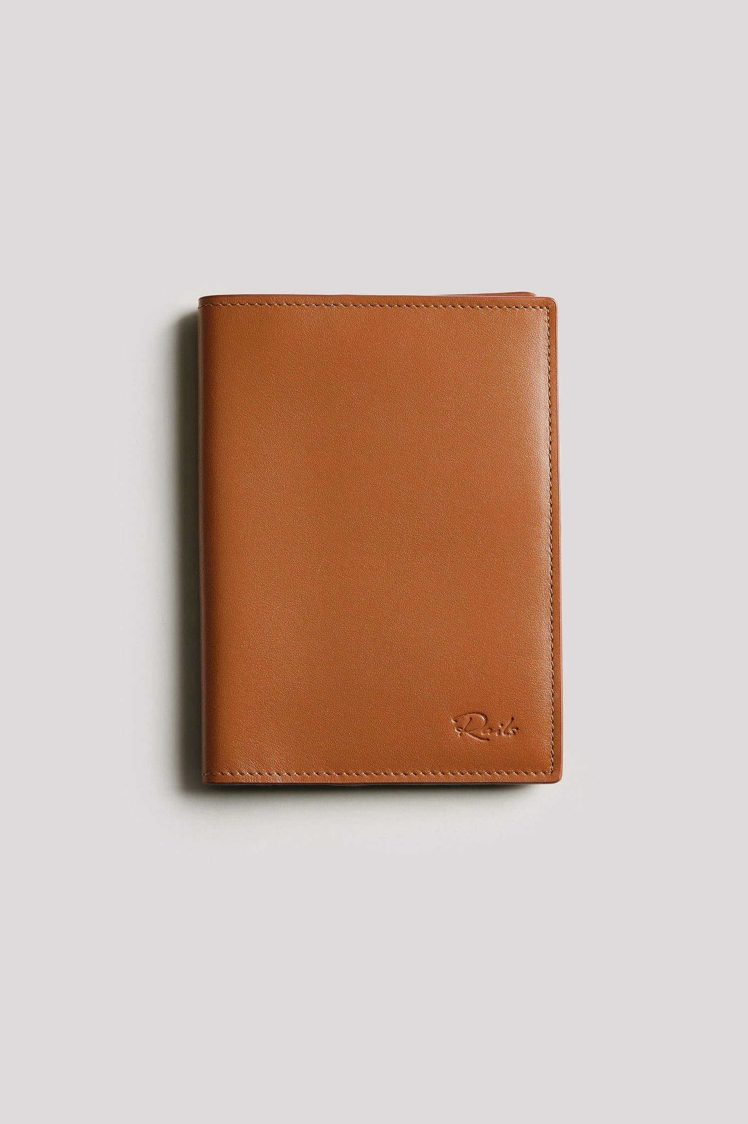 Leather passport holder folded, front view, in brown Cognac colorway.