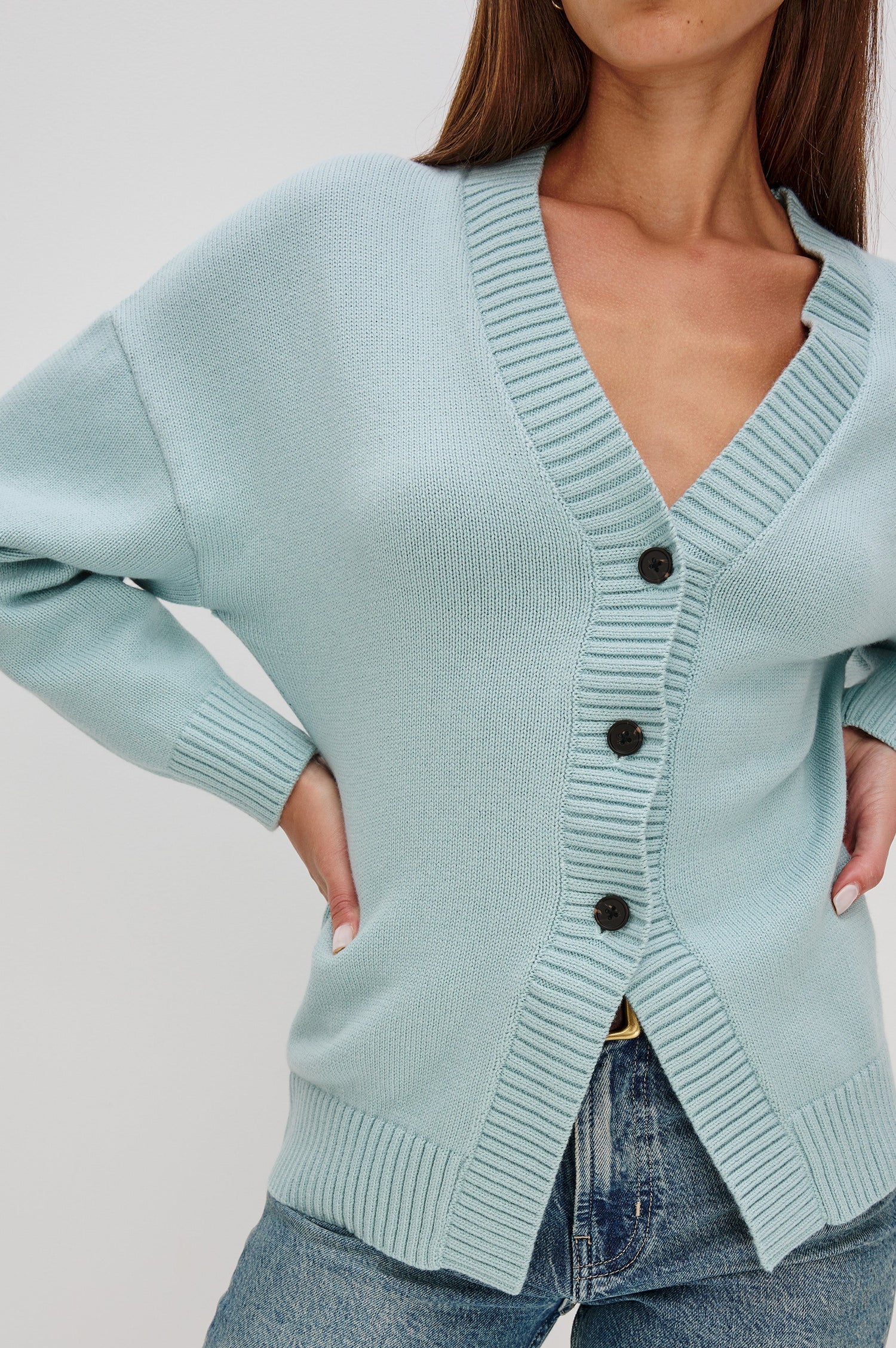 Longline cardigan in a cotton-wool blend in Stone Blue Colorway. The design features drop shoulders and a front cutaway detail, creating a soft, relaxed, and flattering silhouette. Close Up View on Model.