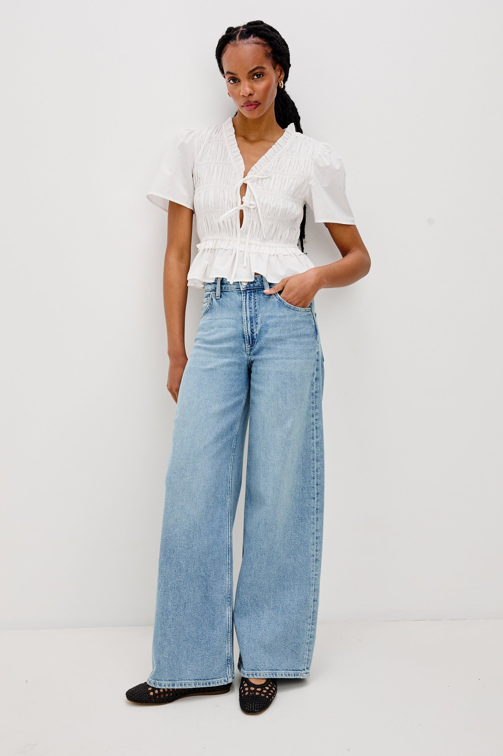 Portia V-Neck Tie Front Top with Short Puff Sleeves and a Ruffled Peplum Hem in White Colorway. Full Body Front View Shown on Model.