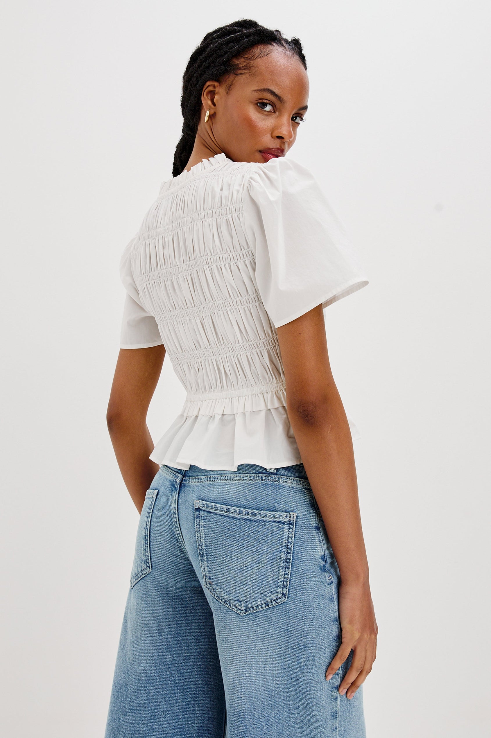 Portia V-Neck Tie Front Top with Short Puff Sleeves and a Ruffled Peplum Hem in White Colorway. Back View Shown on Model.