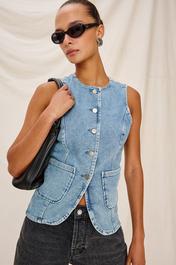Portola Sleeveless Denim Vest with Exposed Button Front Closure, Crew Neck, Front Patch Pockets and a Scalloped Split Hem in Blue Eyed Girl Colorway. Full Body Front View Shown on Model.