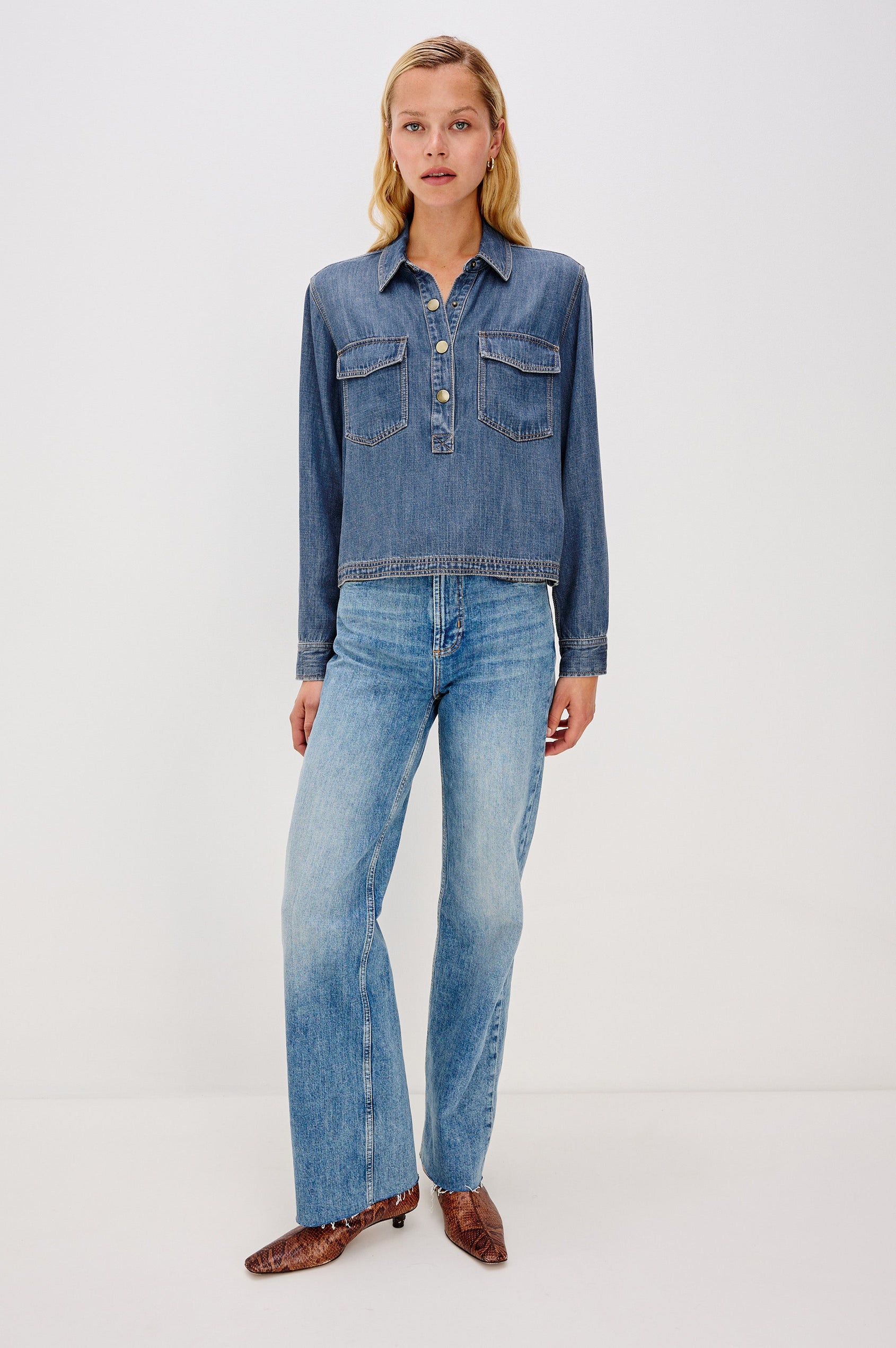 Ports is a soft, lightweight denim shirt with a cropped fit. The shirt features a half placket with snap-front closures, short sleeves, and two chest pockets in Antique Blue Colorway - Full Body Front View on Model