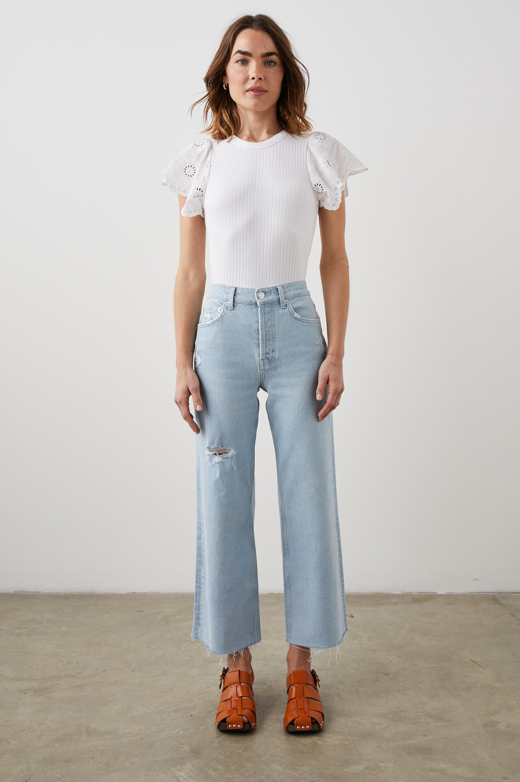Reza Ribbed Short Sleeve Top with Flutter Sleeves, a Crew Neck and Floral Eyelets on the Sleeves in White Colorway - Front Tucked Full Body View Featured on Model 