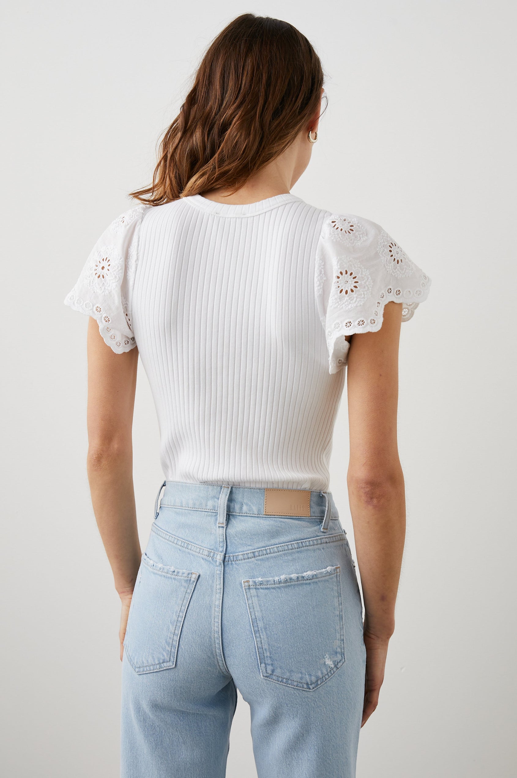 Reza Ribbed Short Sleeve Top with Flutter Sleeves, a Crew Neck and Floral Eyelets on the Sleeves in White Colorway - Back Tucked View Featured on Model 