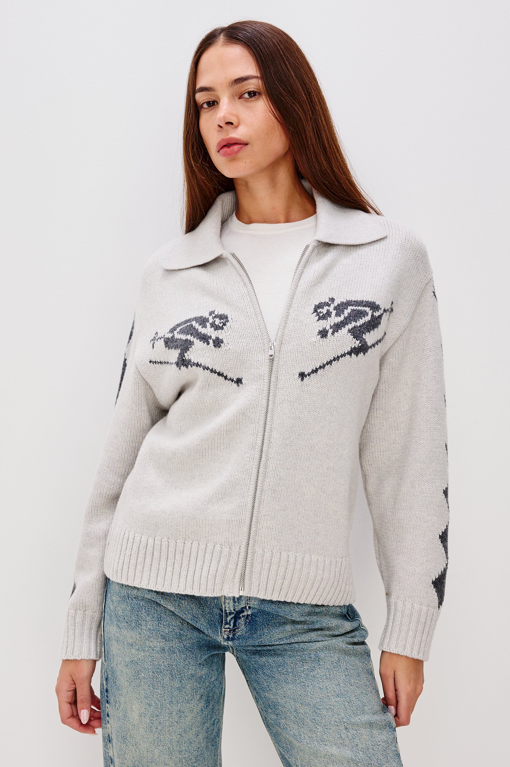 Rhea, a longline cardigan in a wool blend with skier motifs in Powder Grey Colorway. The cardigan has a relaxed fit and zip-front closure. Front View Featured on Model, Zipped Up