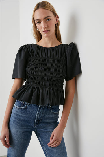 Rosie Short-Sleeve Top with a Smocked Center Bodice, Pleats at the Hem and Yoke and a Upper Back Tie Closure in Black Colorway - Front View Featured on Model
