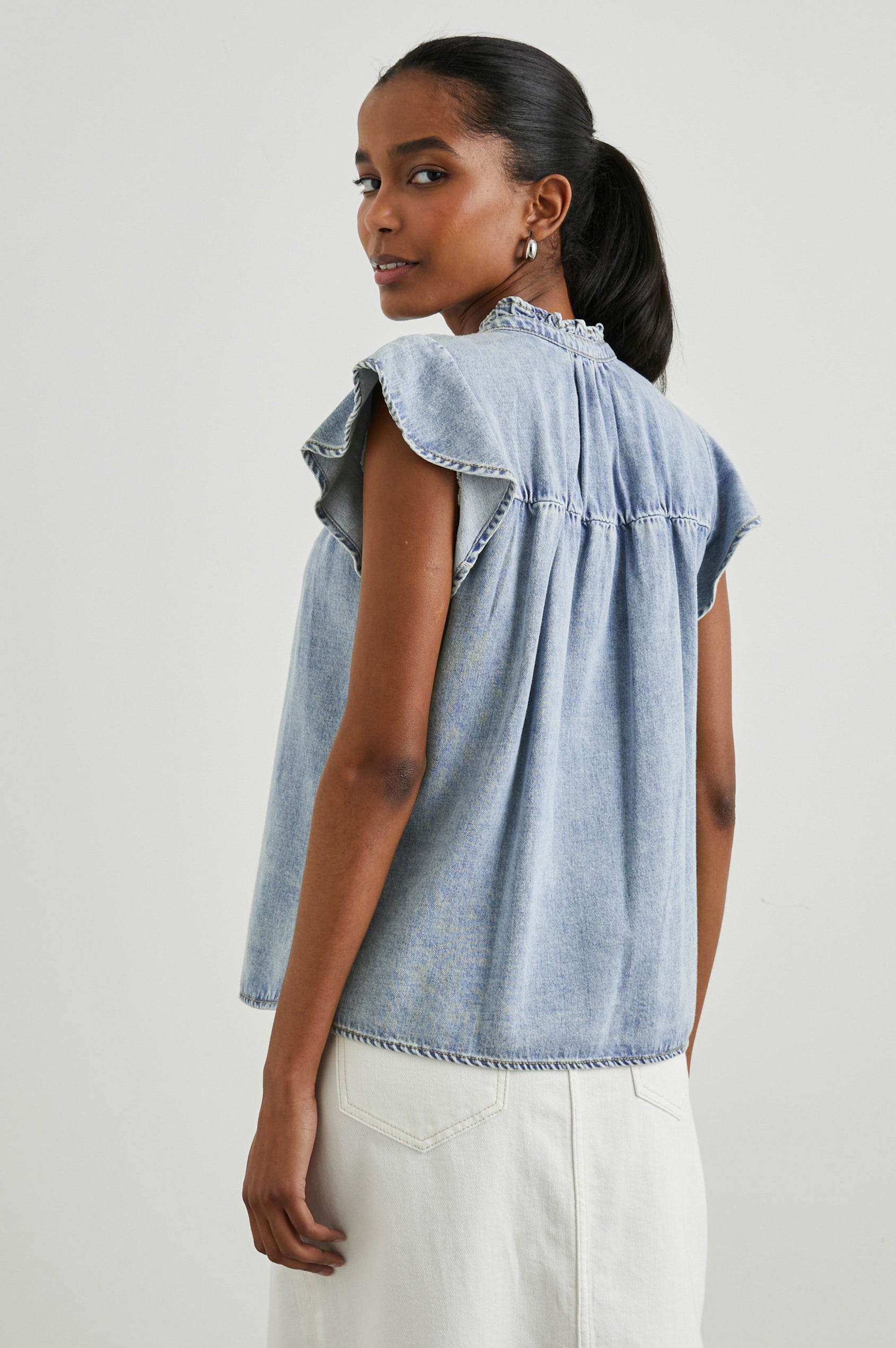 Ruthie Top with Flutter Cap Sleeves, a Ruffled Banded Collar, Buttons Down the Front, and Soft Shirring at Front Yoke in Faded Indigo Colorway - Back  View Featured on Model