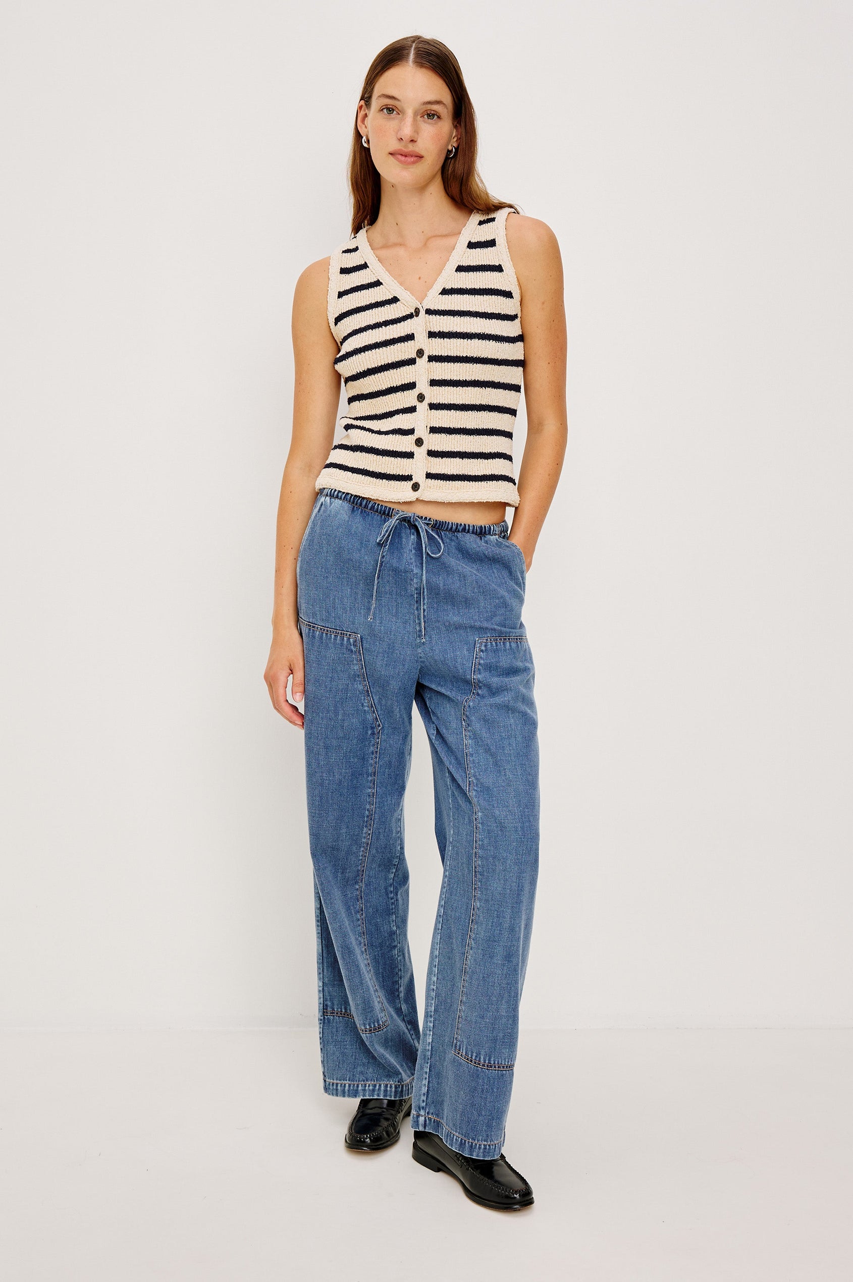 The Sade is a button front sweater vest with a v-neck in Ivory Navy Stripe colorway. Front full body view featured on model. 