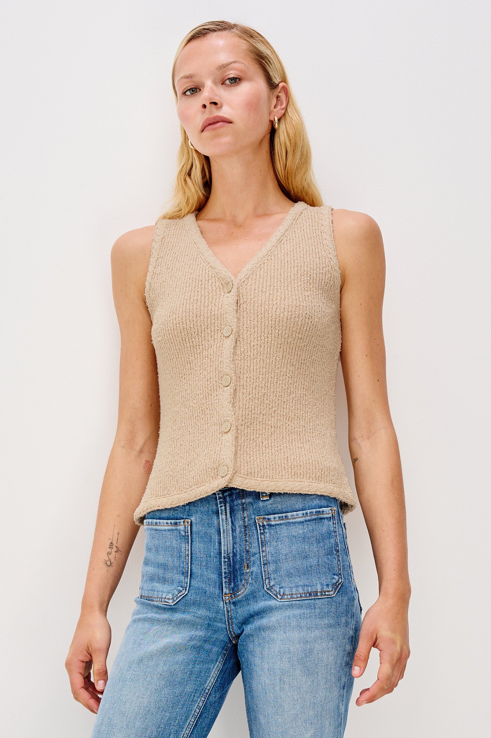 Soft cotton vest in a neutral Oat Colorway. The vest features subtle ribbing, a full-button front, and is styled on its own for a clean, minimalist look. Front view featured on model.