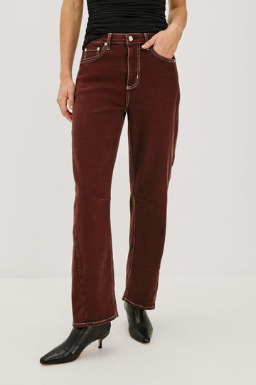 The Samo is a denim barrel leg jean, it features a low-slung fit in light-stretch denim with darting details and a subtle curved seam in Chocolate Contrast Stitch colorway. Front view featured on model.