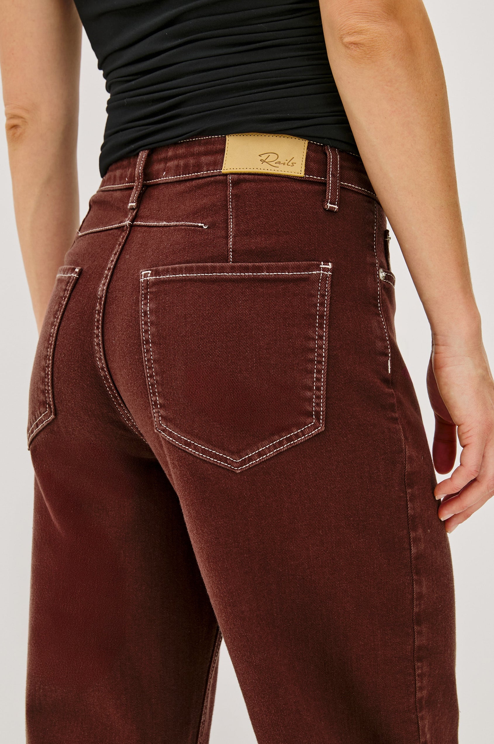The Samo is a denim barrel leg jean, it features a low-slung fit in light-stretch denim with darting details and a subtle curved seam in Chocolate Contrast Stitch colorway. Front view featured on model.