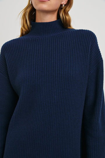Sanna Long Sleeve Knit Sweater with a Funnel Neck and Slits at the Back of the Neck and on the Cuffs in Dark Slate Colorway - Front View Featured on Model
