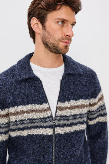 Seldon is a zip front collard sweater jacket with a multi color horizontal stripe design across chest in Moon Shadow colorway. Front detail view featured on model.