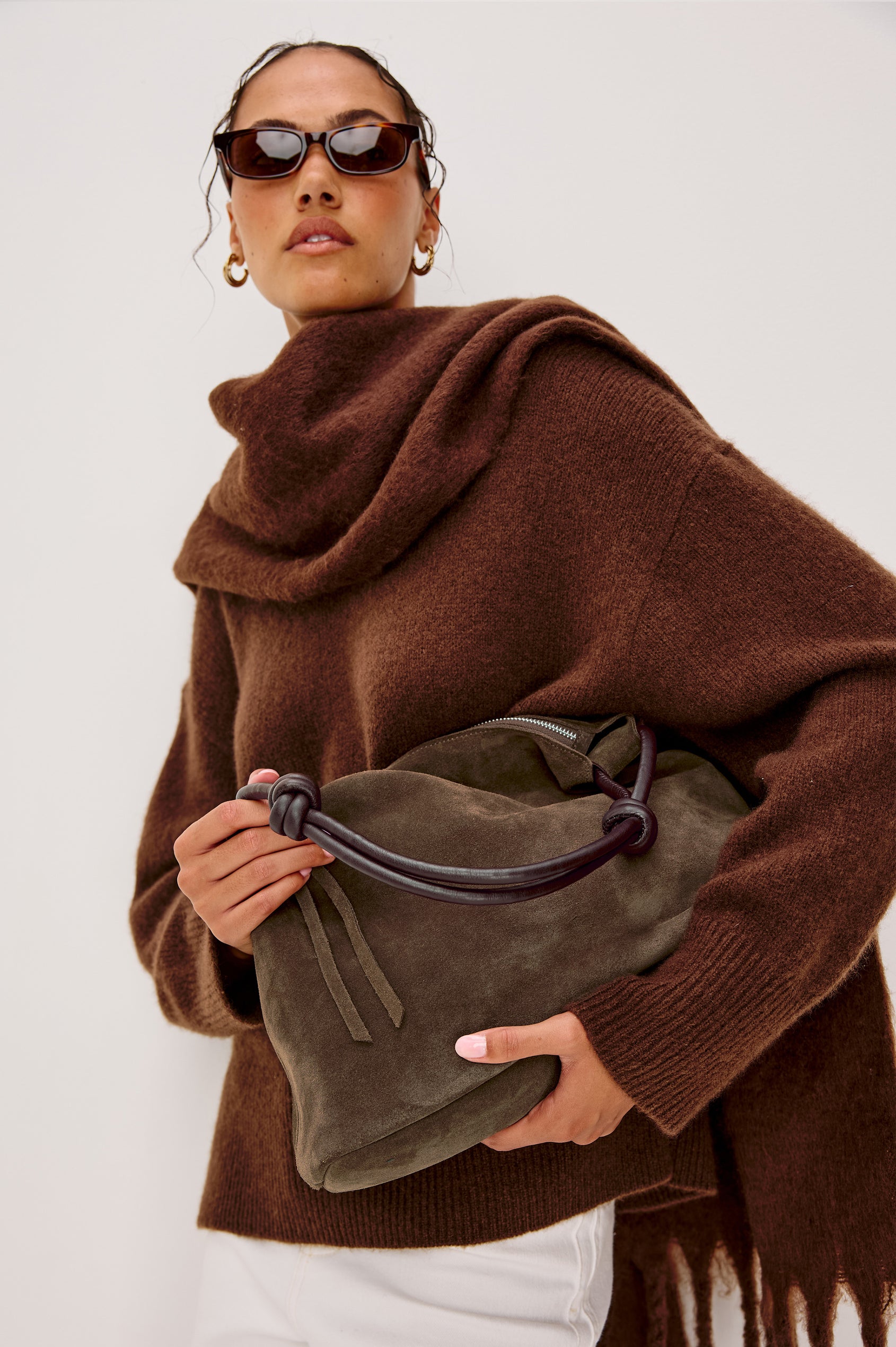 The Siena is a true slouchy hobo bag, crafted from smooth leather with a knotted top strap and a zip closure finished with a fringed tassel. In Espresso Suede Colorway. Front view featured on model.