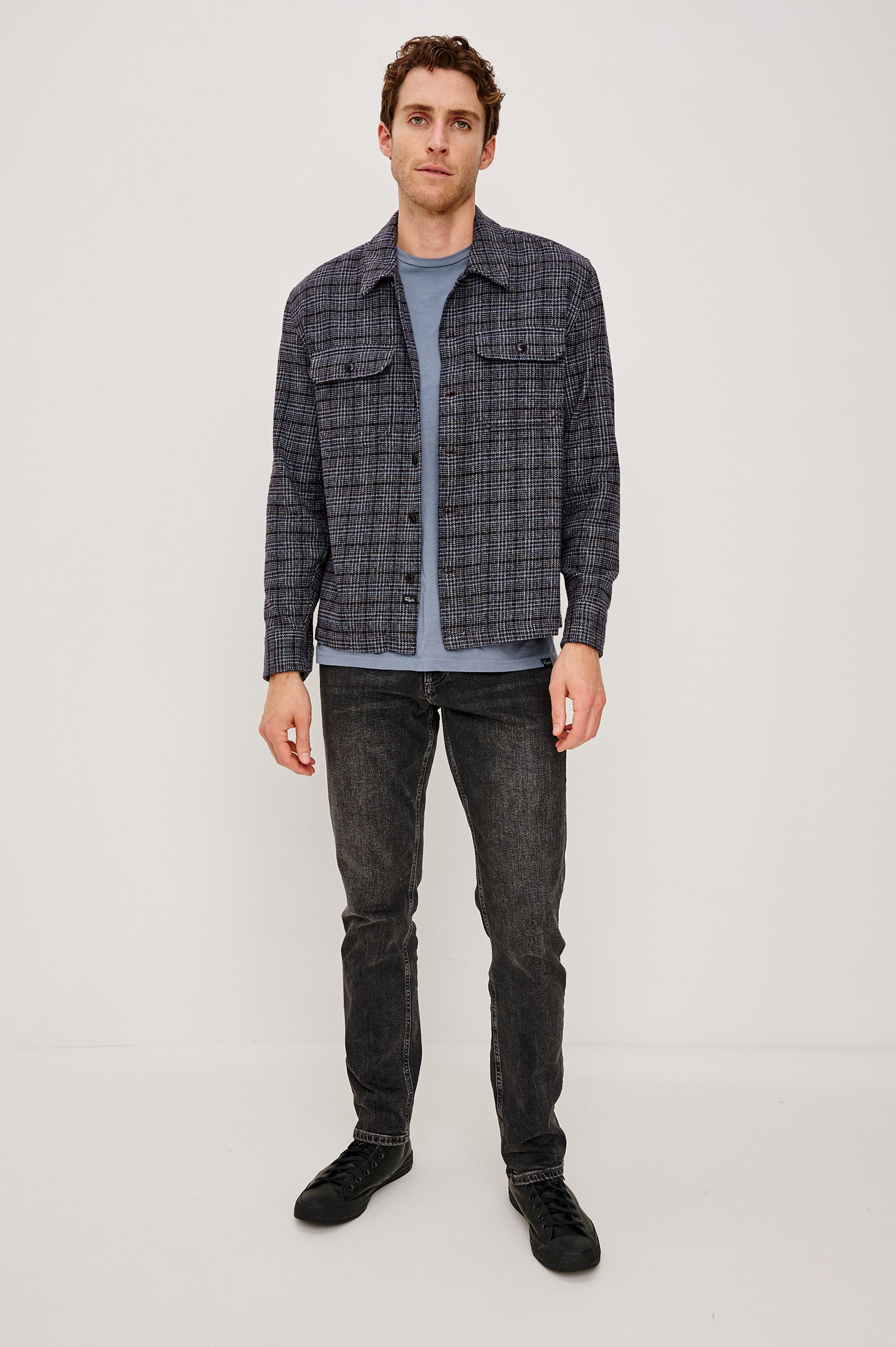 Stellan is a shirt jacket made from heavy brushed cotton with a classic collar, front button closures, chest flap pockets in Cedar Bay, a blue and grey plaid colorway. Front full body view featured on model.