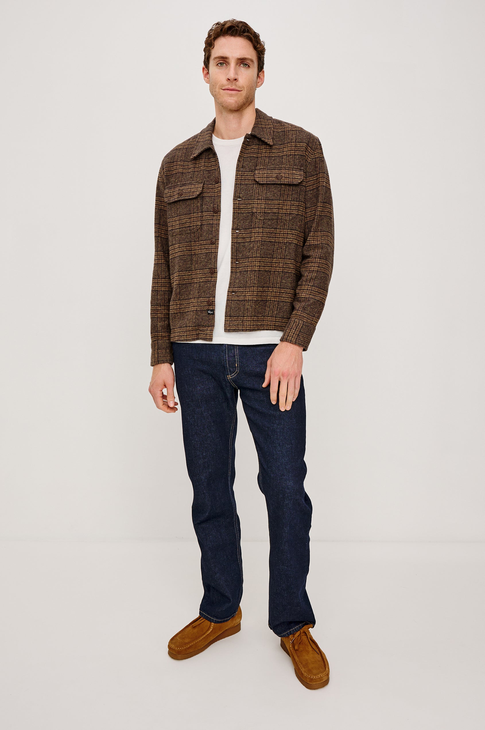 Stellan is a shirt jacket made from heavy brushed cotton with a classic collar, front button closures, chest flap pockets in Cedar Bay, a blue and grey plaid colorway. Front full body view featured on model.