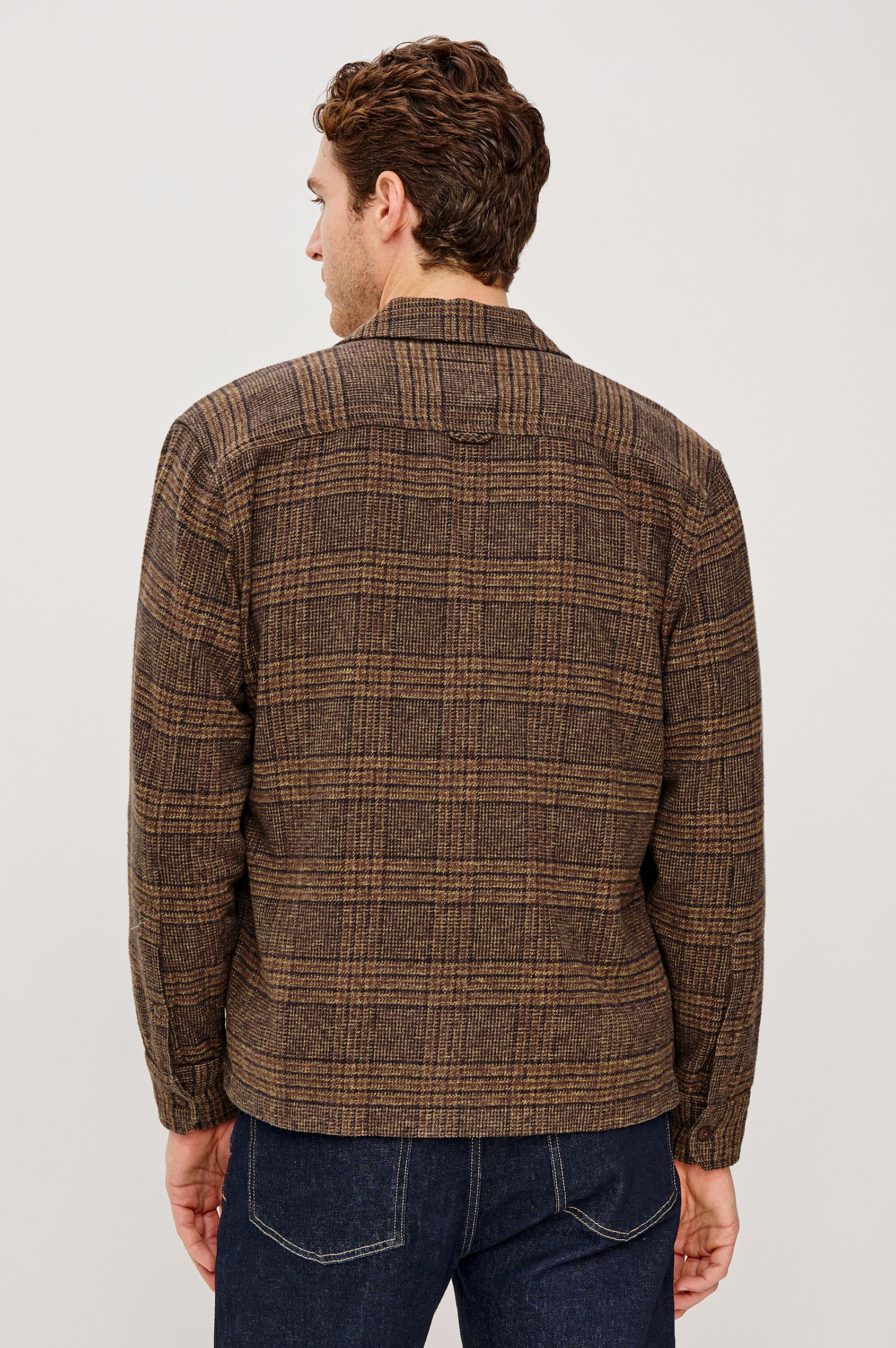 Stellan is a shirt jacket made from heavy brushed cotton with a classic collar, front button closures, chest flap pockets in Cedar Bay, a blue and grey plaid colorway. Back view featured on model.