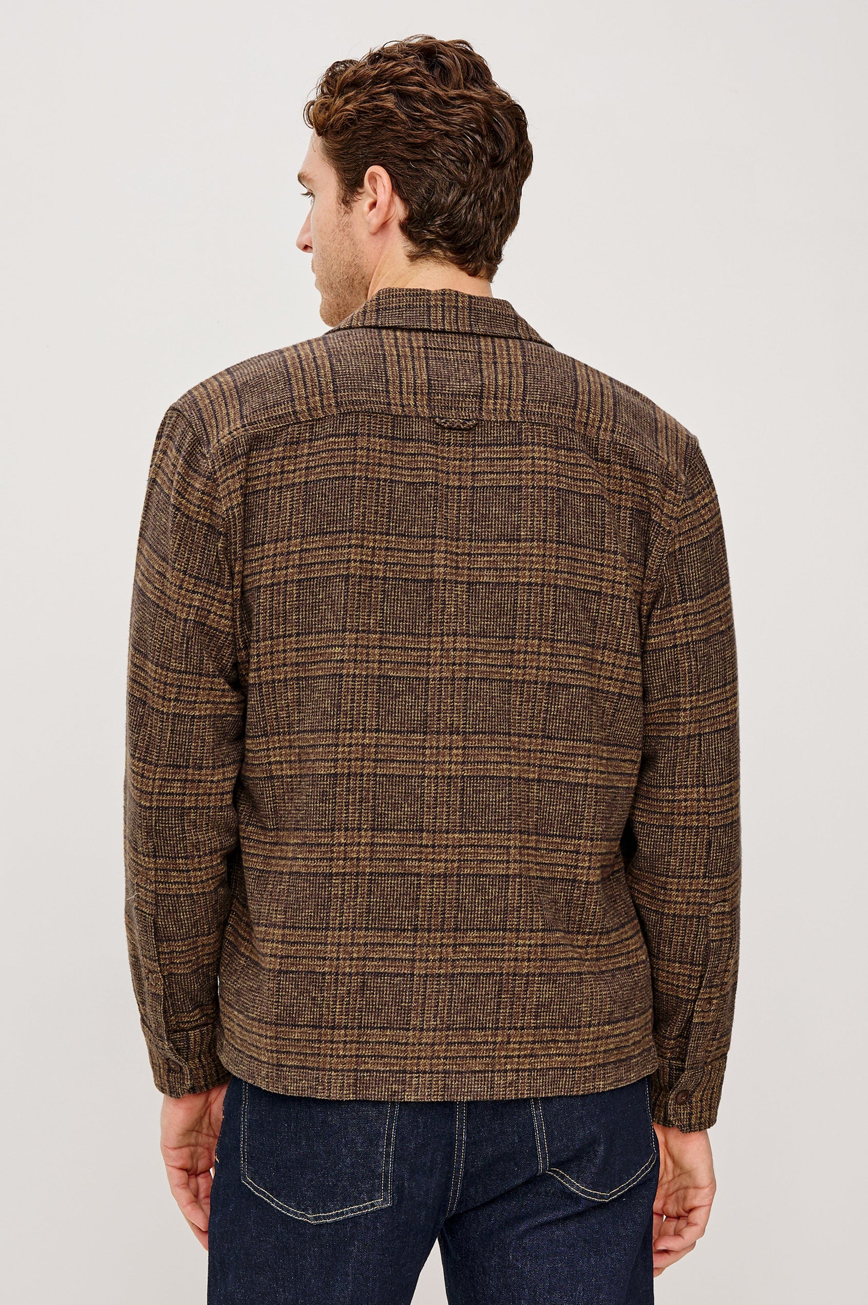 Stellan is a shirt jacket made from heavy brushed cotton with a classic collar, front button closures, chest flap pockets in Cedar Bay, a blue and grey plaid colorway. Back view featured on model.
