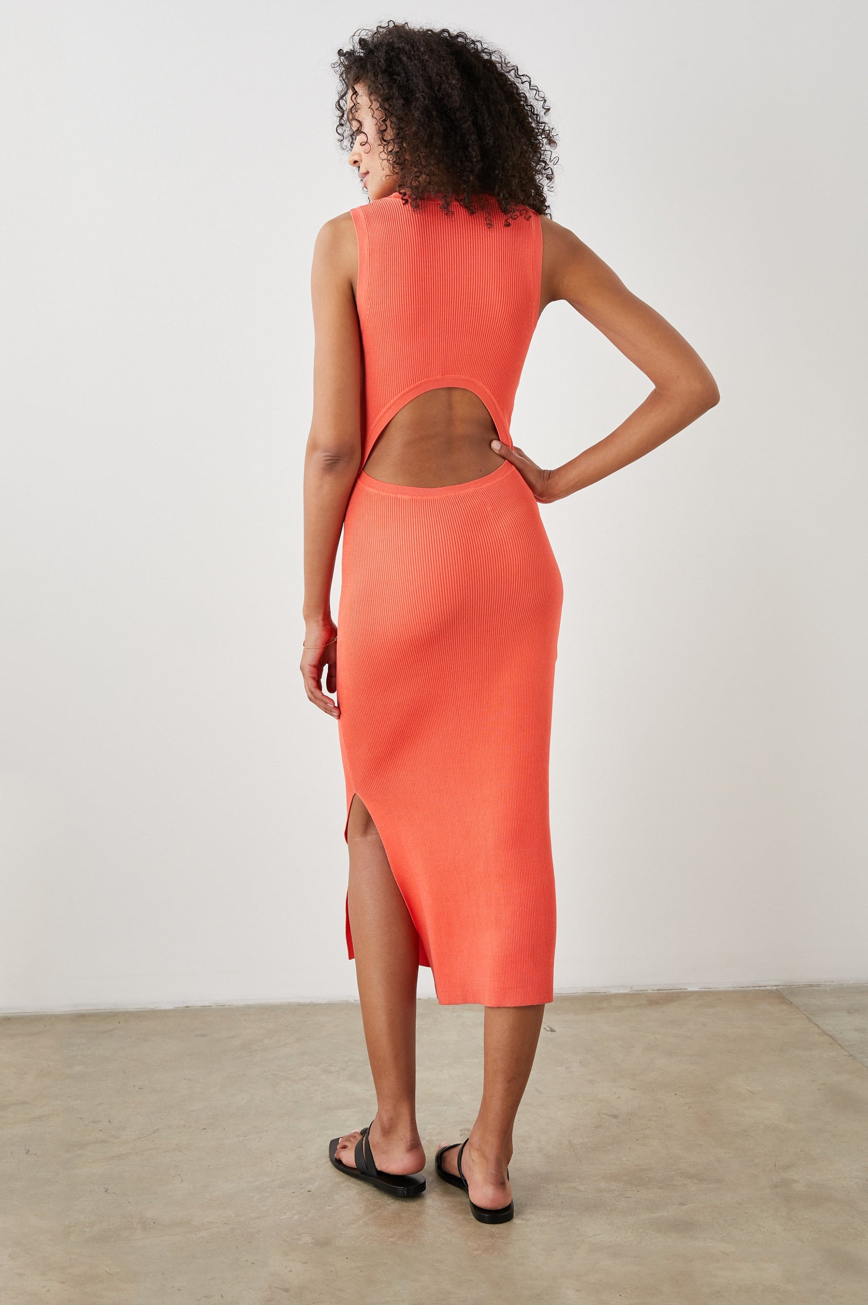 Syd Ribbed, Sleeveless Midi Dress with Wide Shoulder Straps, a Side Slit, and a Cutout that Spans the Lower Back in Black Colorway - Back Full Body View Featured on Model  
