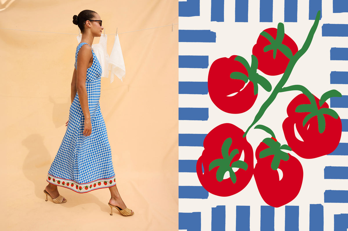 Woman in a blue dress standing next to a decorative panel with red tomatoes on a beige background