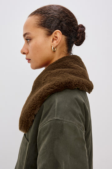 An umber waxed cotton canvas jacket with a removable vegan-fur collar. The jacket has a zip front with snap closures, quilted lining, chest patch pocket, and side pockets for a functional, workwear-inspired look. Close Up View Featured on Model.