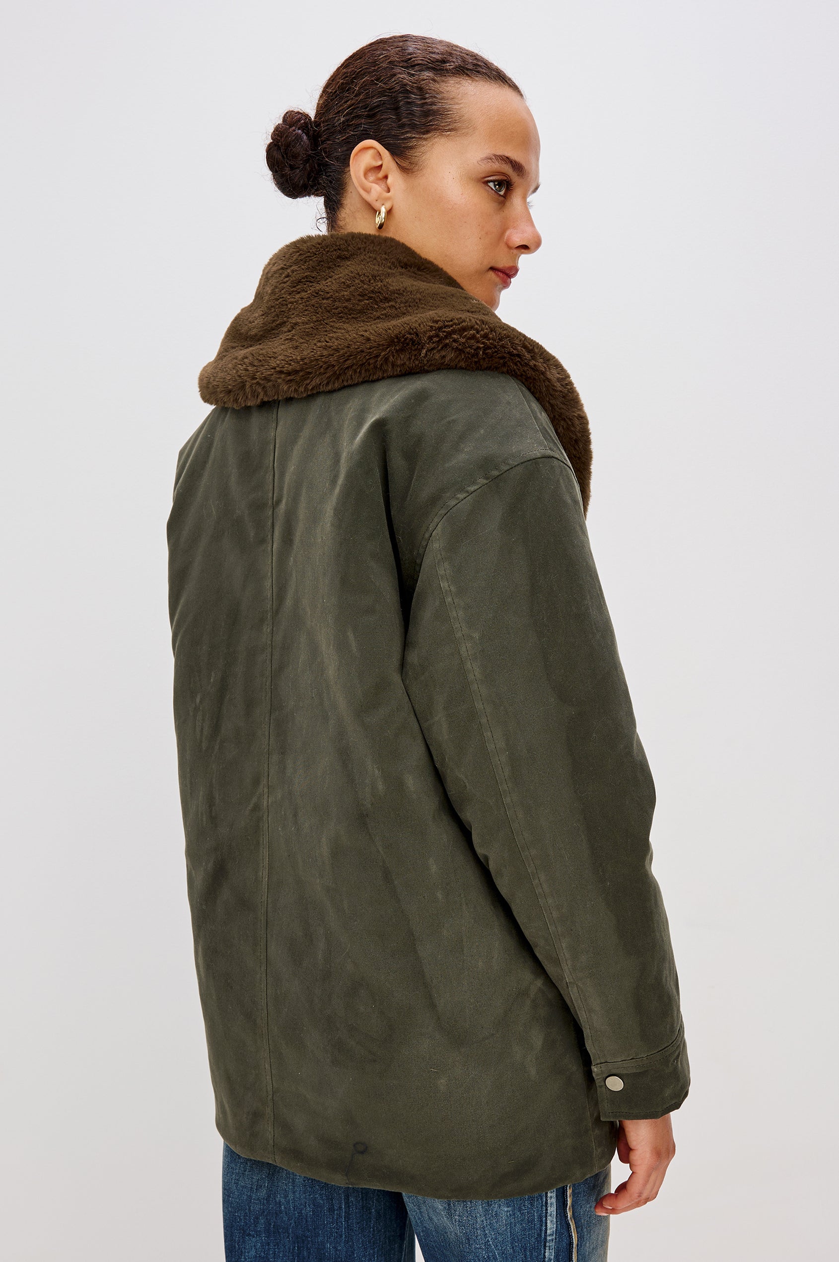 An umber waxed cotton canvas jacket with a removable vegan-fur collar. The jacket has a zip front with snap closures, quilted lining, chest patch pocket, and side pockets for a functional, workwear-inspired look. Back View Featured on Model.