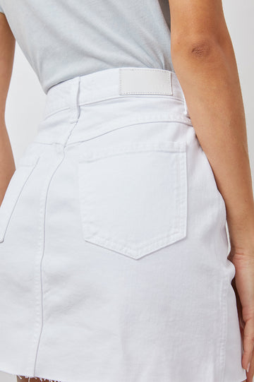 Canyon Denim Mini Skirt with a Full Button Front, Belt Loops, Light Fraying along the Hem, Two Front Pockets and Two Back Patch Pockets in Salt White Colorway - close up of back details on model