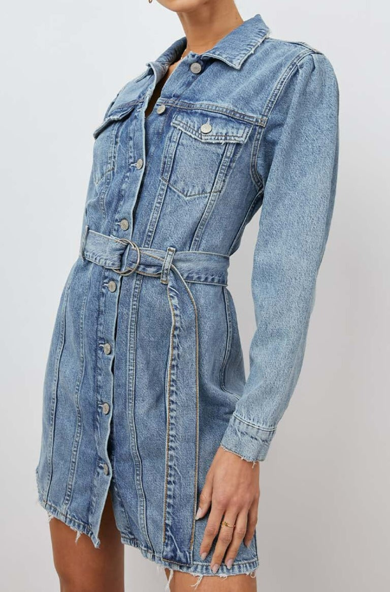 Griffith Long-Sleeve Denim Mini Dress with Buttons Down the Front, a Fabric Double Ring Belt, Two Chest Button Flap Pockets, Frayed Trim and Vertical Seams Down the Front in Indigo Charm Colorway - Front View Featured on Model 