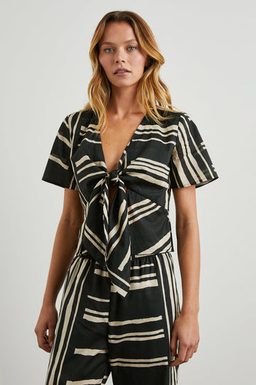 Tia Short-Sleeve Top Closed with a Front Tie and a Deep V Neck in Island Stripe Colorway, Cream Horizontal and Vertical Stripes on Black - Front View Featured on Model