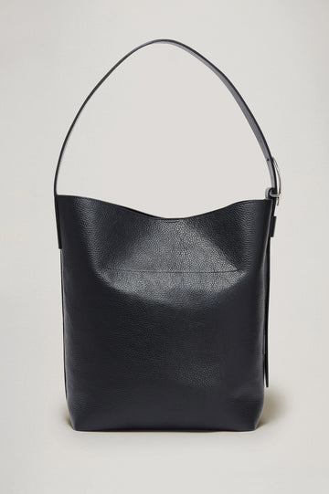 Torino Bucket Bag in Italian Pebbled Leather With Adjustable Strap and Polished Silver Oval Buckle, Microsuede Lining, Interior Magnetic Closure, Snap Button-Slip Pocket, and Subtle Branded Detailing in Black Colorway - Side Close Up Branded Detail View Featured