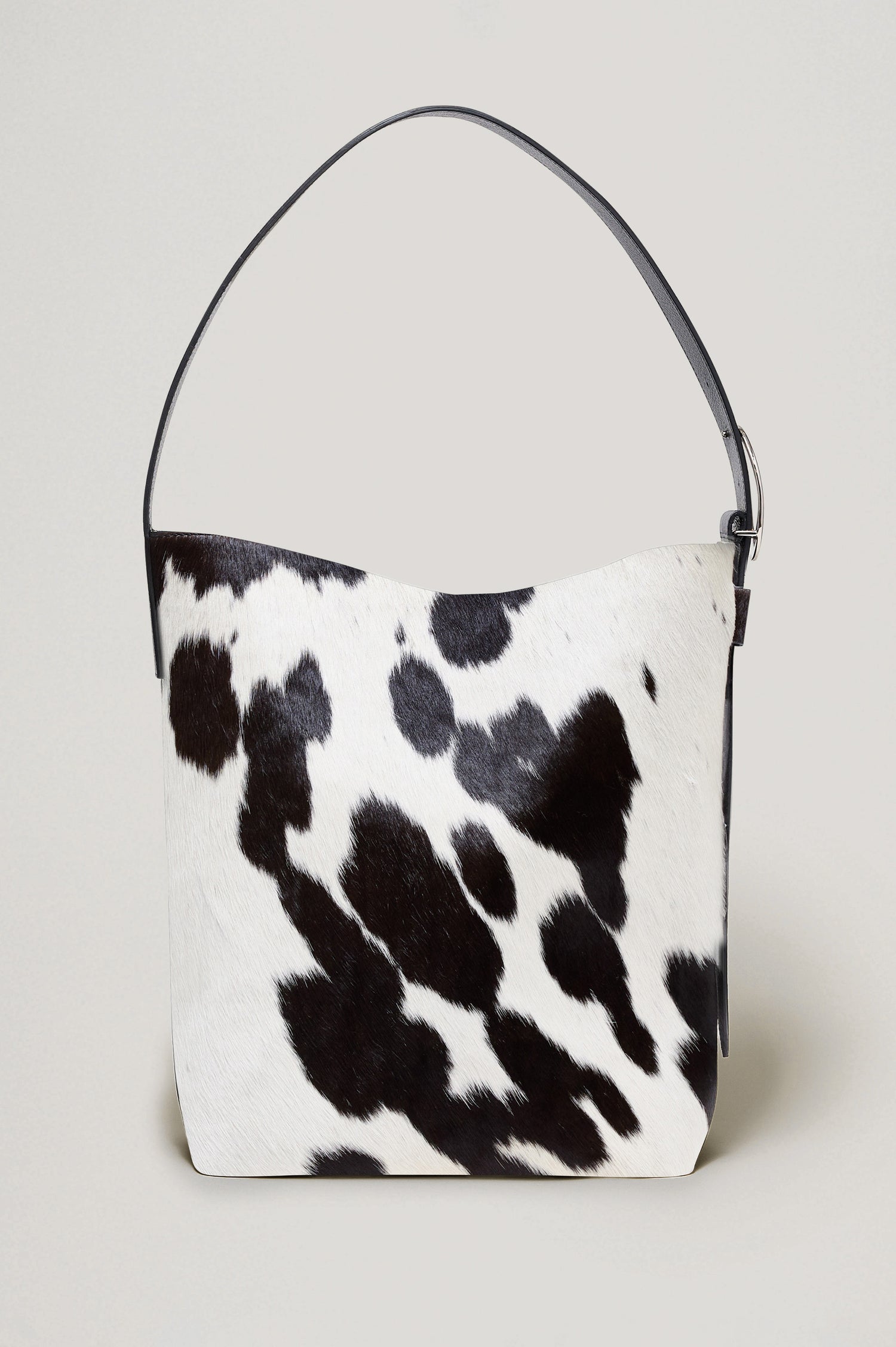 Torino Bucket Bag in Cow Print Haircalf With Adjustable Strap and Polished Silver Oval Buckle, Microsuede Lining, Interior Magnetic Closure, Snap Button-Slip Pocket, and Subtle Branded Detailing in Cowgirl Haircalf Colorway Colorway - Side Close Up View Featured