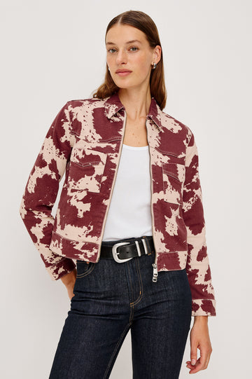 The Trabuco is a collared two-way zip front jacket with two chest pockets and a western style yoke in Cowgirl colorway - a red and beige cow print. Front view featured on model.