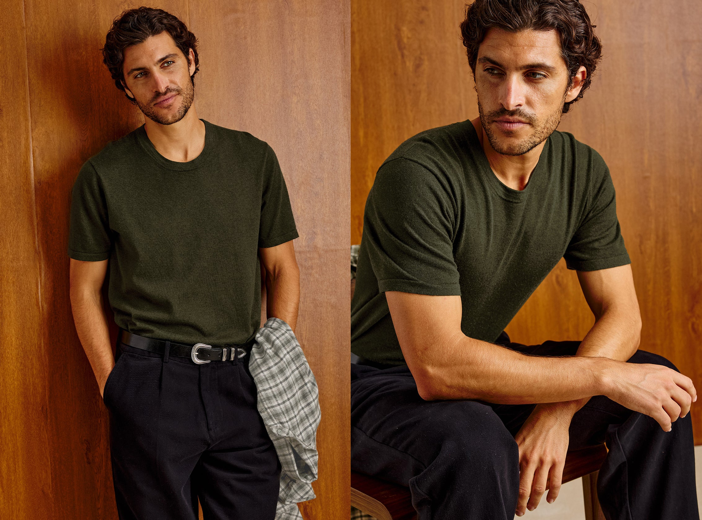 A man modeling an olive green short-sleeve crewneck t-shirt in a split-screen portrait, standing against a wood-paneled wall on the left and sitting on a stool on the right, wearing dark trousers and holding a plaid shirt.