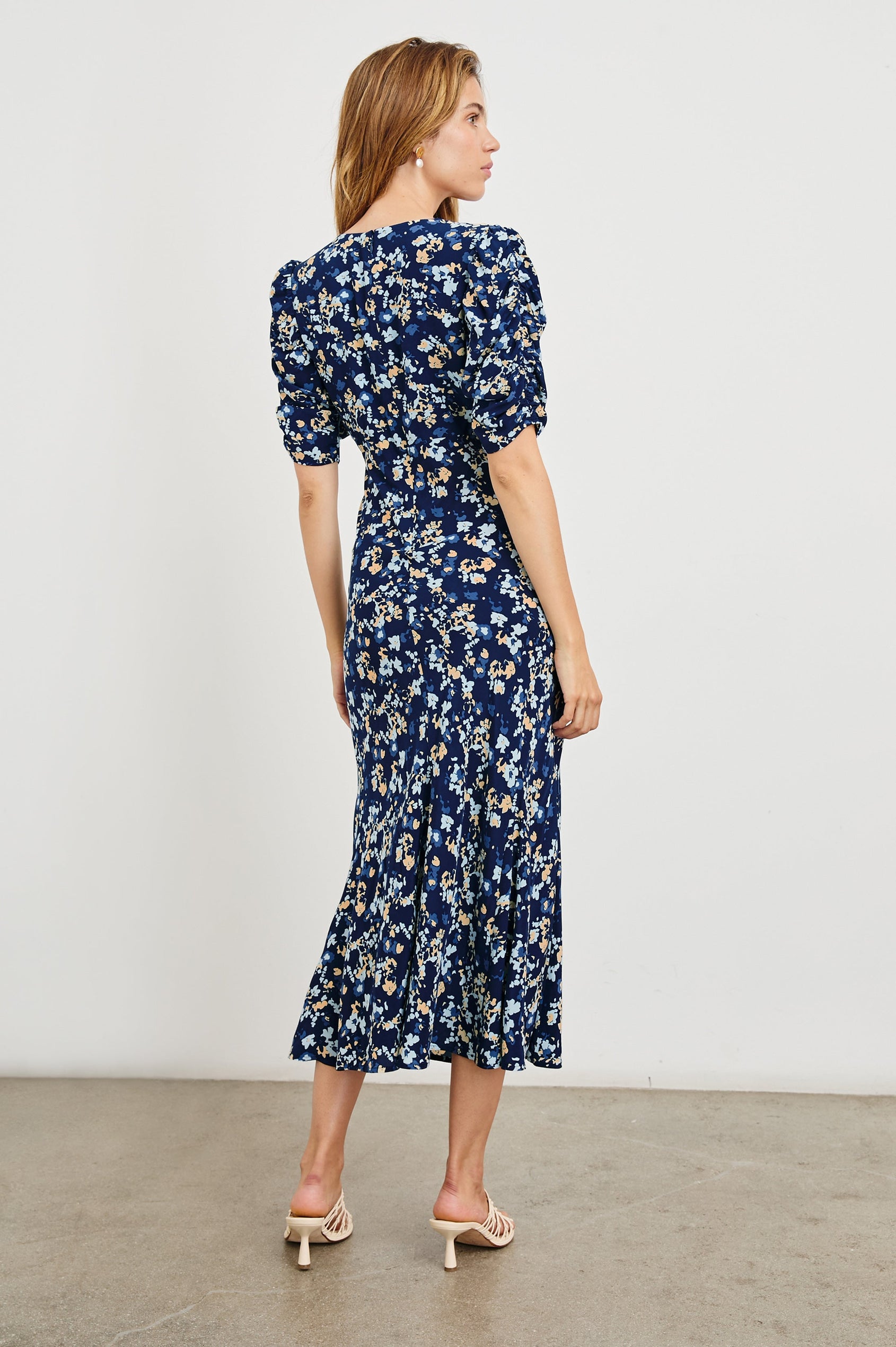Zariah Midi Dress with Mid-Length Sleeves with Light Ruching, a Deep V Neck and an Empire Waist in Navy Flora Colorway, flowers in orange and blues on Navy - Back Full Body View Featured on Model