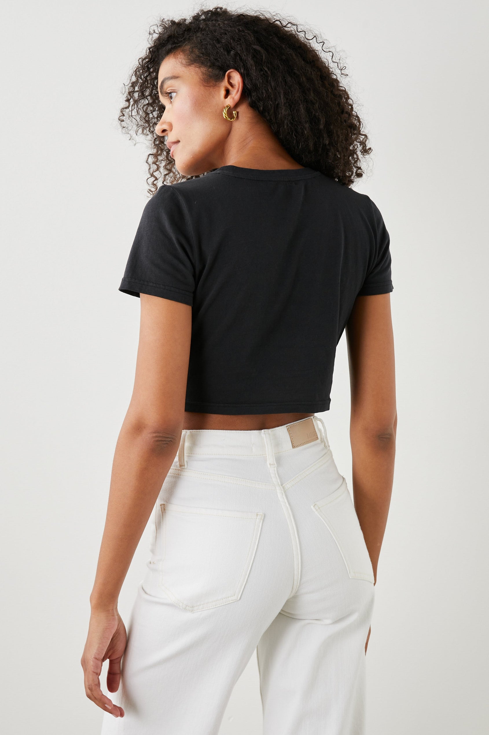 Zena Short-Sleeve Cropped T-Shirt with a Crew Neck and a Circular Cutout with a Tie at the Front Hem in Black Colorway - Back View Featured on Model 