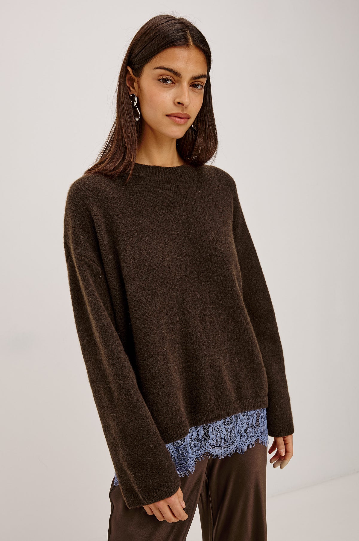 Zoie Sweater in Merino Wool Blend With Contrast Lace Inset Hem for Layered Look, Long Sleeves, and Slightly Oversized Fit in Espresso Blue Lace Colorway - Front View Featured on Model.