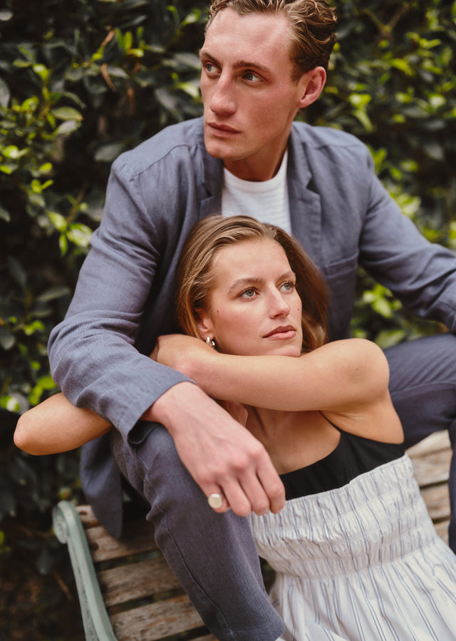 Man and woman sitting closely together outdoors with greenery in the background