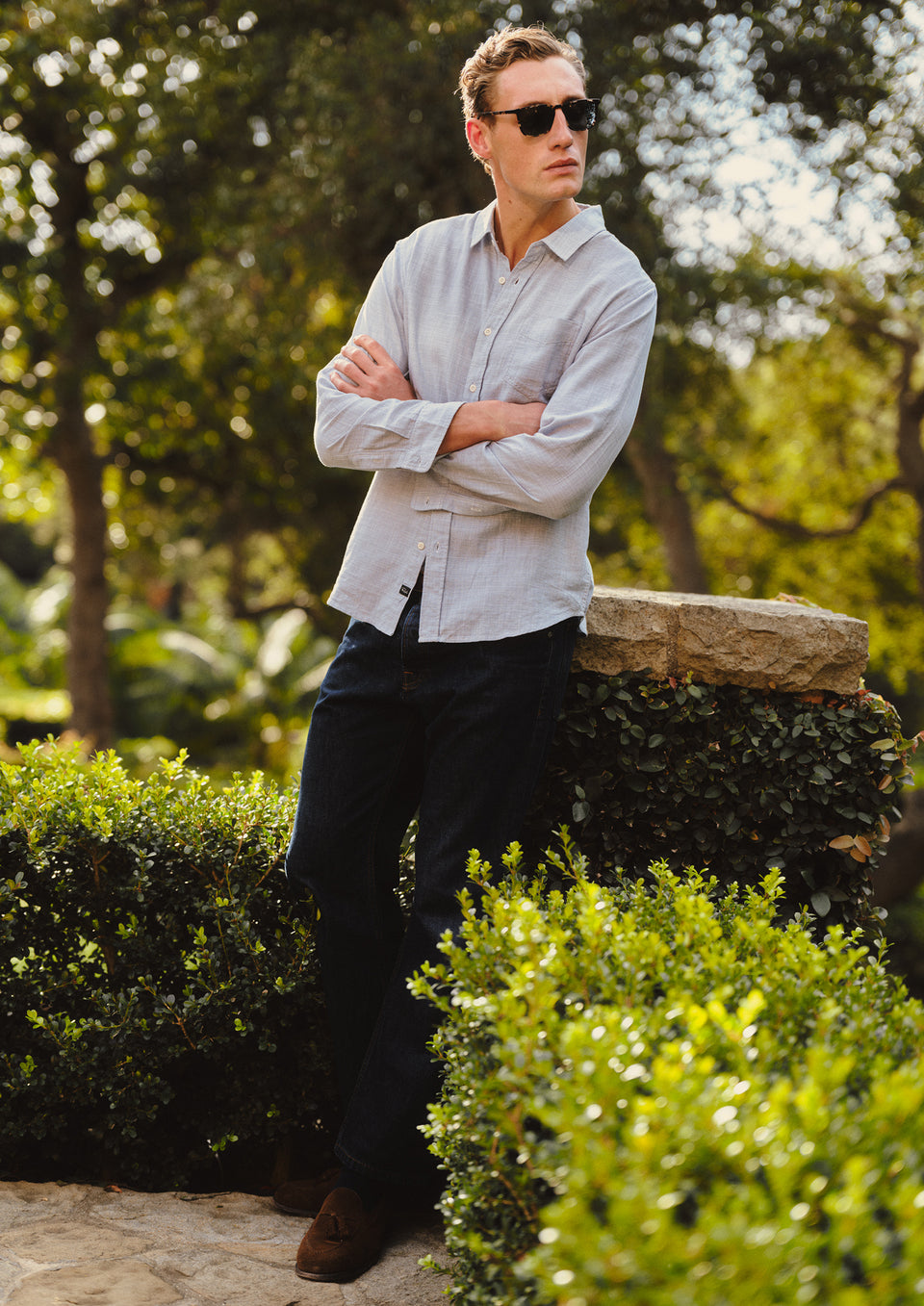 Man wearing sunglasses and a light shirt standing in a garden