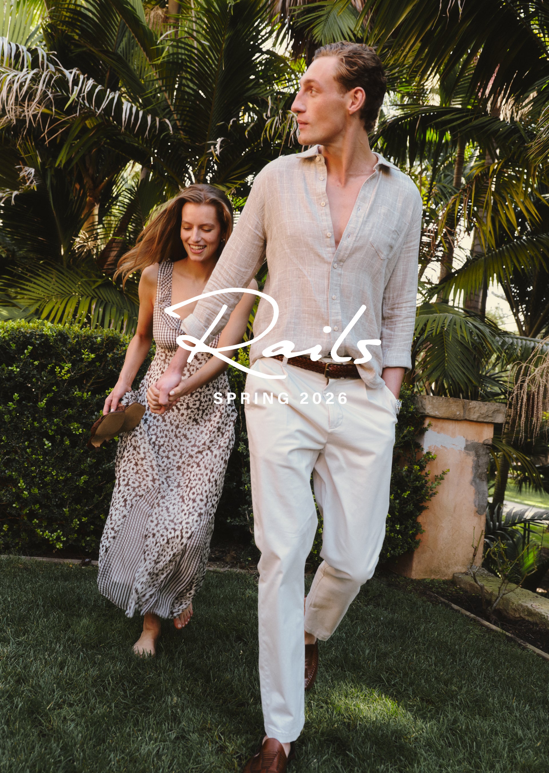 Two people walking together in a garden setting with ' Rails' branding.