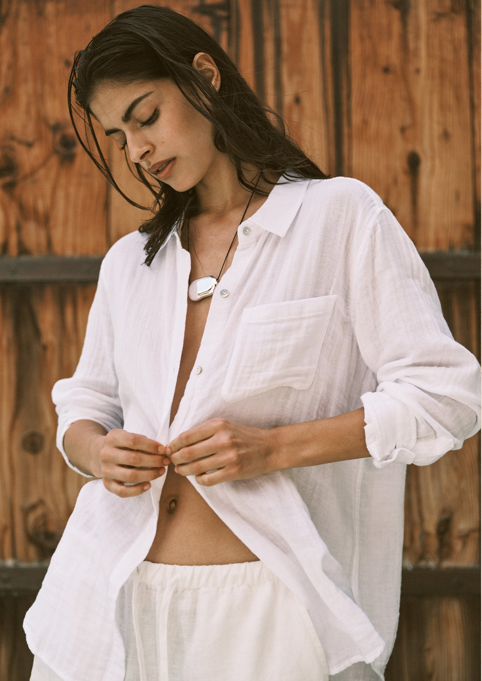 Woman wearing a white shirt and pants against a wooden background