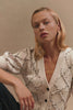 (Video): Isla oversized cardigan in Oat beige, highlighting the chunky knit texture and button details - front close up and detail view featured on model sitting.