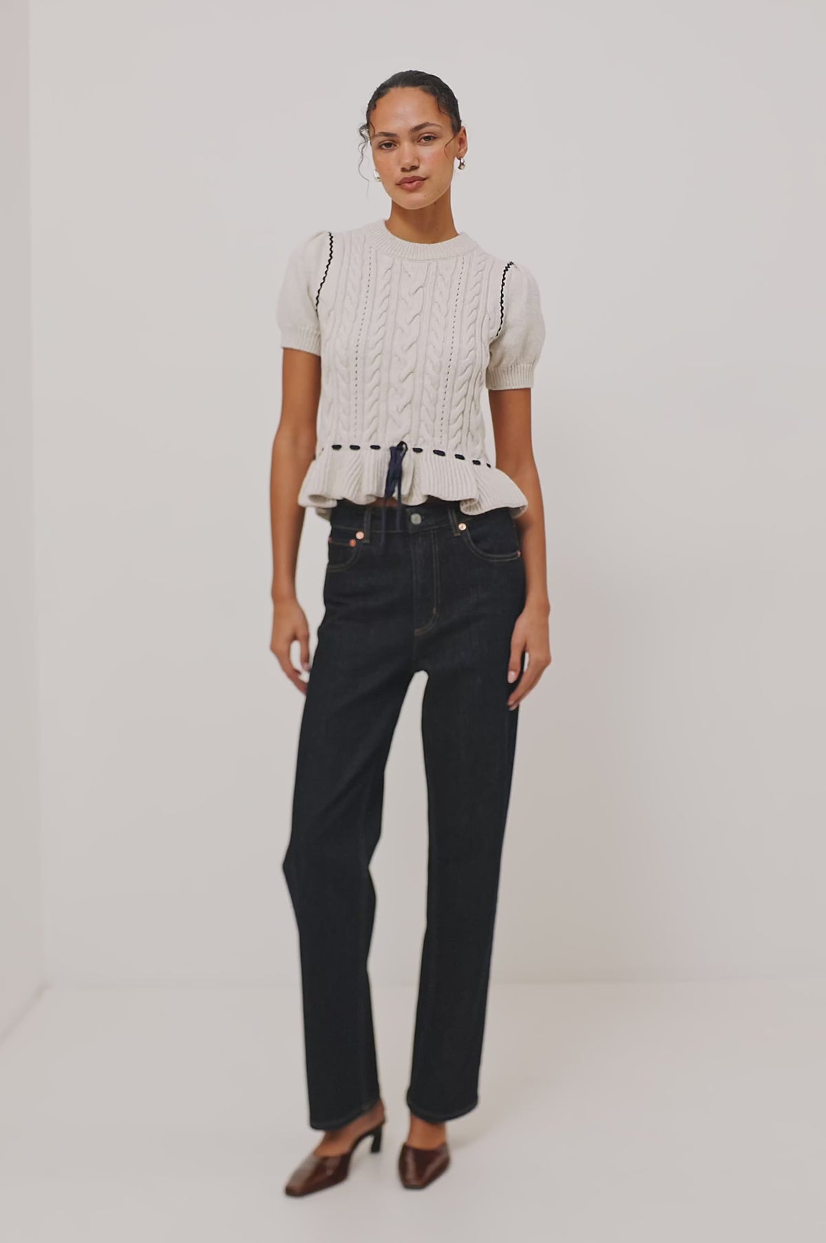 Chandi Sweater in Cable Knit With Short Puff Sleeves, Fitted SIlhouette, Soft Flared Peplum Hem, and Contrast Serpentine Trim and Interlocking Drawstring Ties in Heather Oat Colorway - Video - Full Body Front View Featured on Model