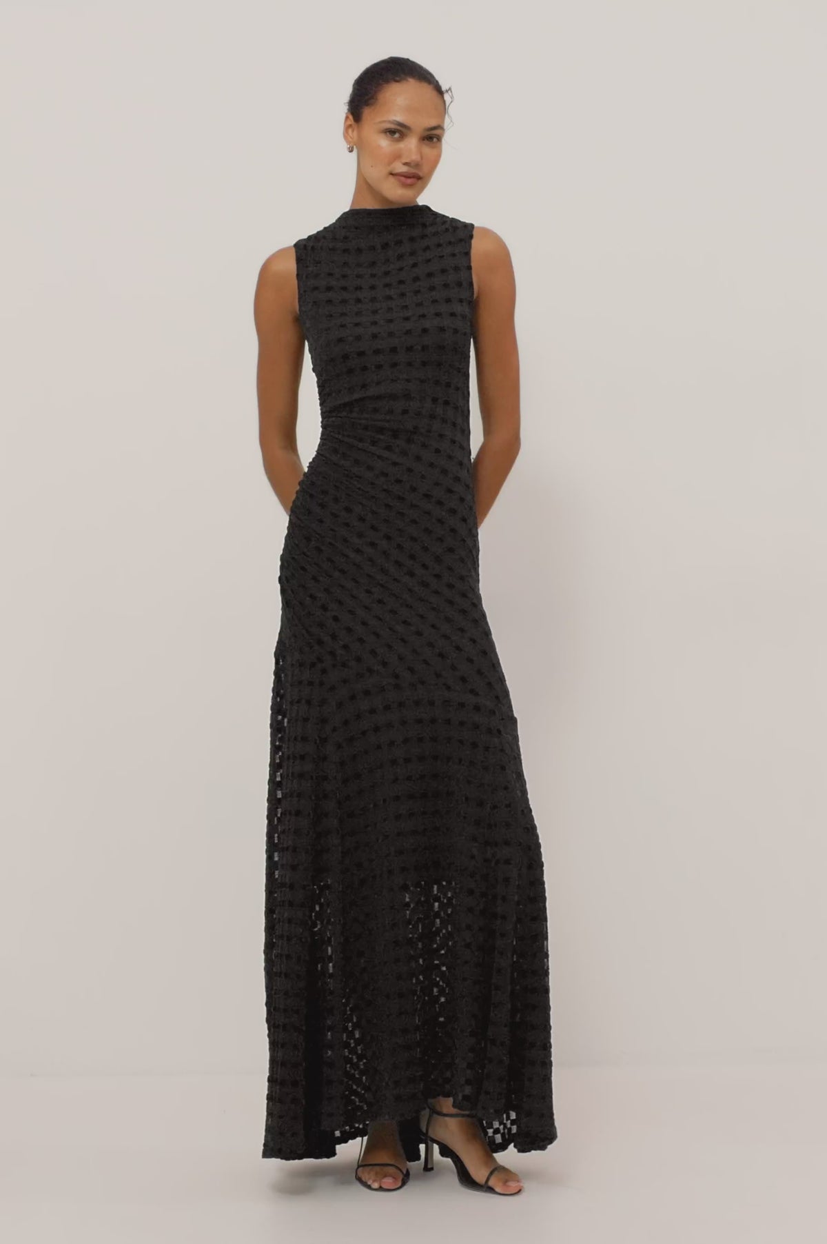 Cosmos Dress in Checkerboard Devoré With Mock Neck, Sleeveless Silhouette, and Ruched Waist in Black Checkerboard Colorway - Full Body View Featured on Model Moving (Video).