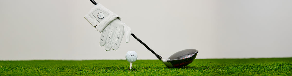 Golf club and glove on grass with a white background