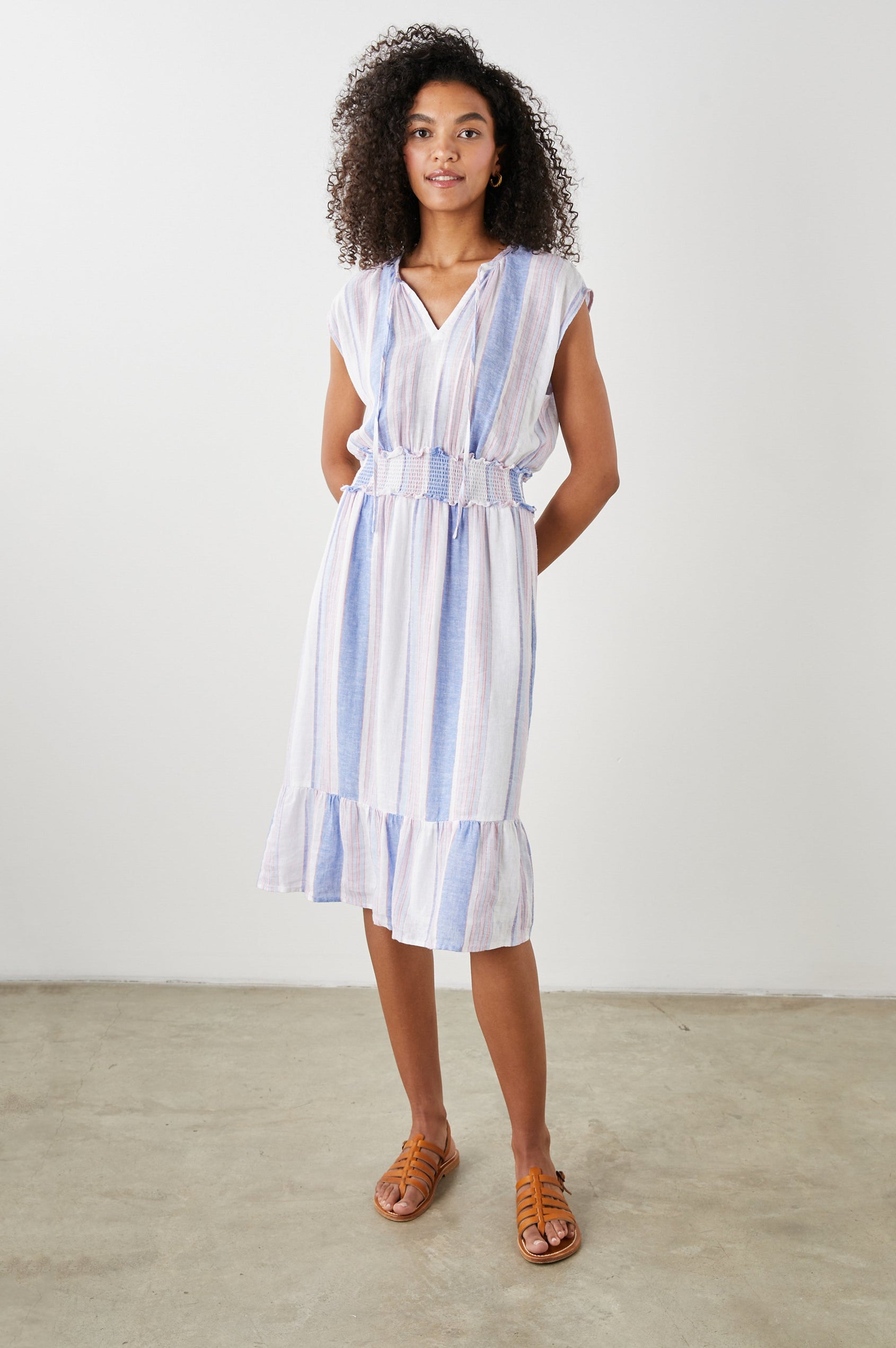 Ashlyn Short Sleeve Midi Dress with a V neck with Ties, a Smocked Waist and a Ruffle Tier at the Hem in Marini Stripe Colorway, Vertical Stripes in Pink and Blue on White - Front Full Body View Featured on Model
