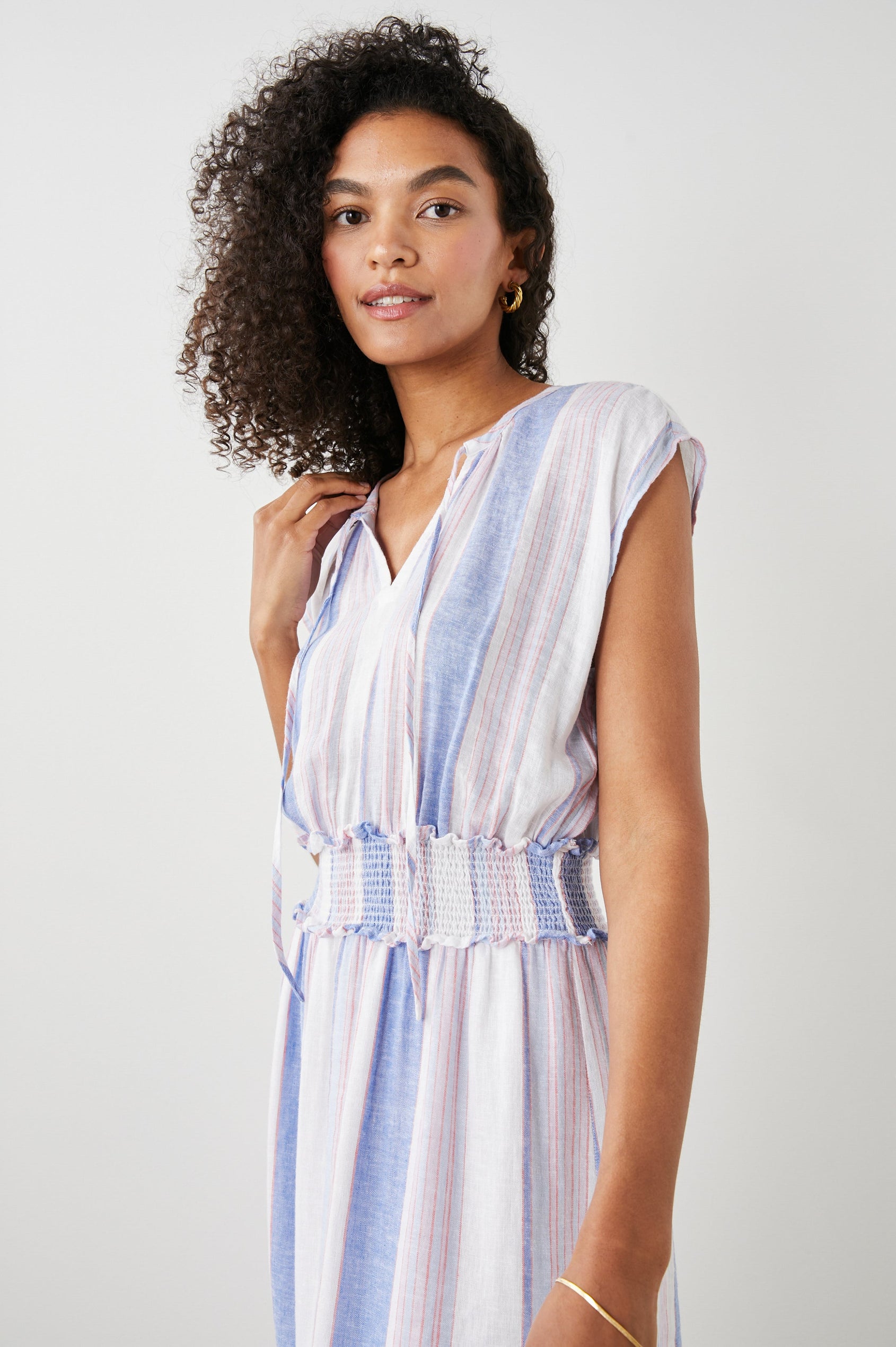 Ashlyn Short Sleeve Midi Dress with a V neck with Ties, a Smocked Waist and a Ruffle Tier at the Hem in Marini Stripe Colorway, Vertical Stripes in Pink and Blue on White - Front View Featured on Model