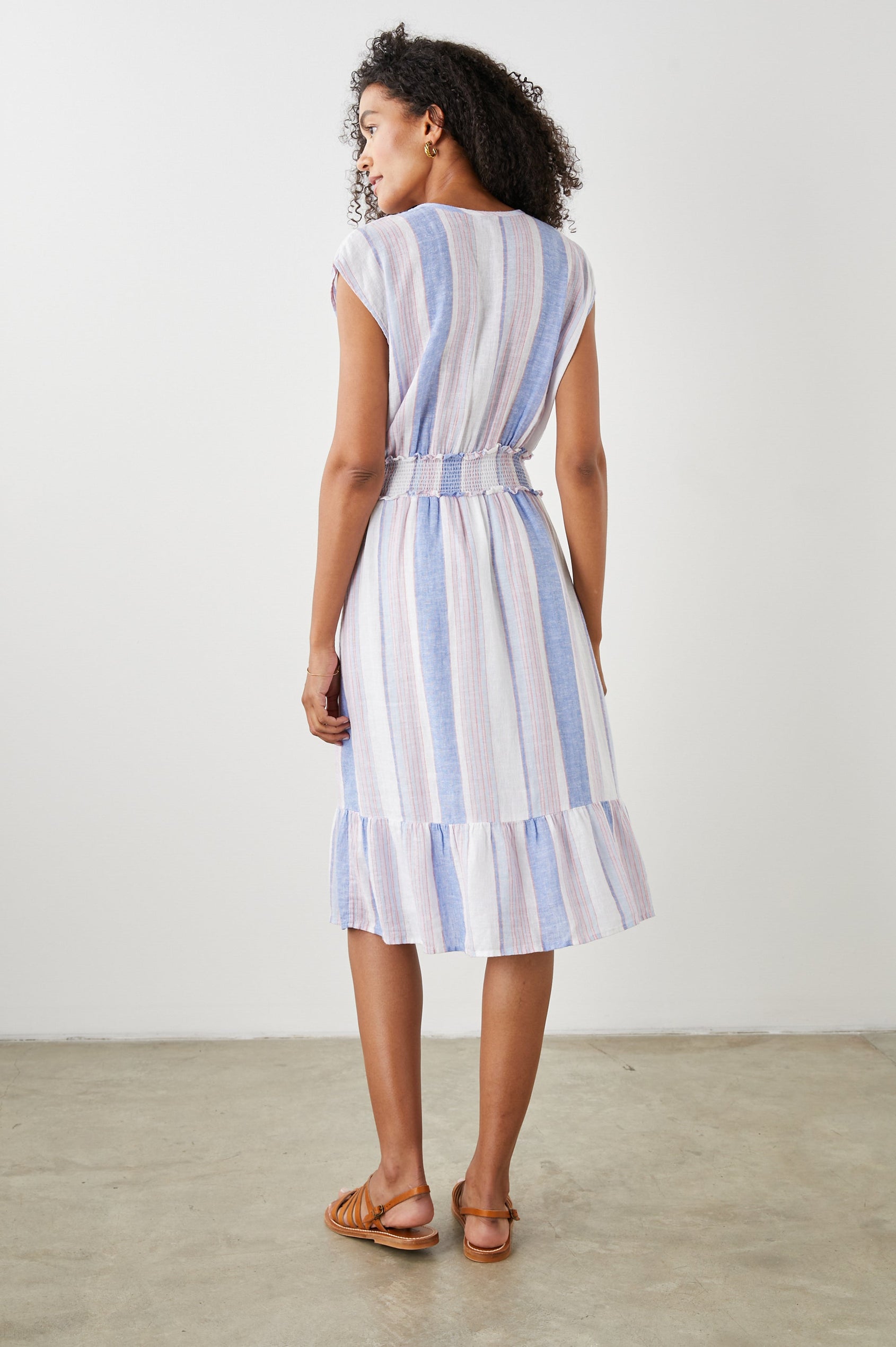 Ashlyn Short Sleeve Midi Dress with a V neck with Ties, a Smocked Waist and a Ruffle Tier at the Hem in Marini Stripe Colorway, Vertical Stripes in Pink and Blue on White - Back Full Body View Featured on Model